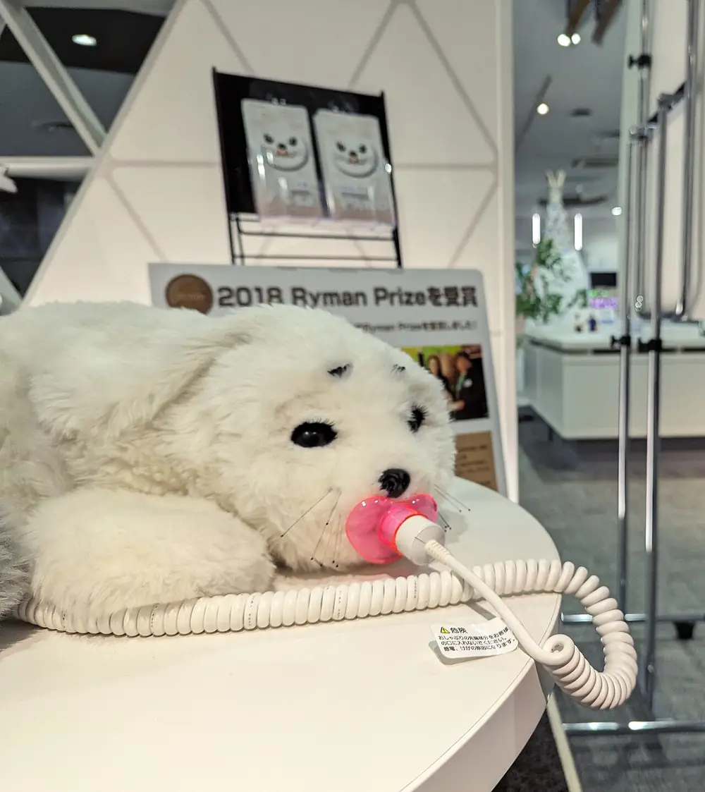 A white PARO seal with its charging pacifier